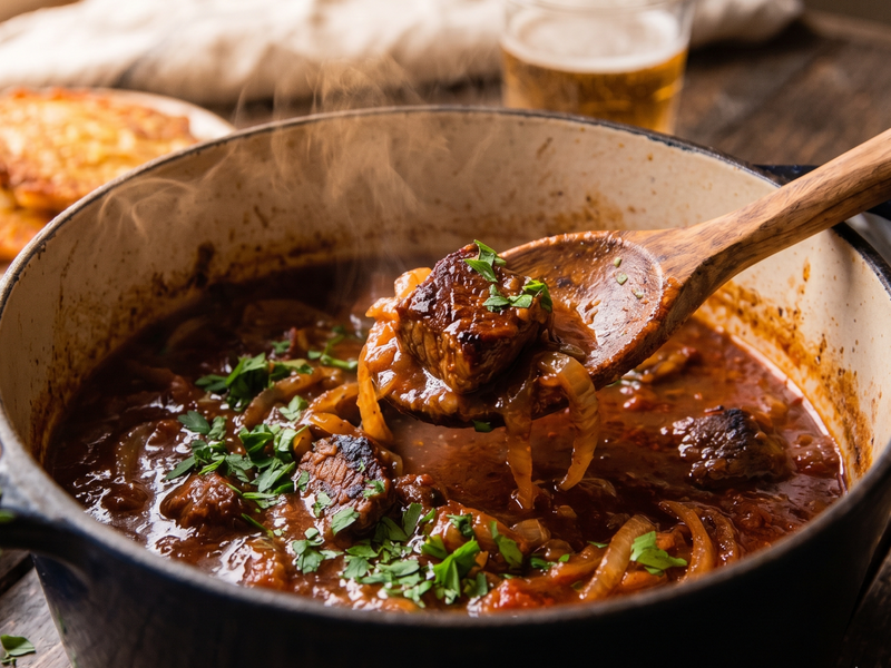 Stew with a wooden spoon in a pot on a wooden table | Cook & Keeper - Gulasz wieprzowy